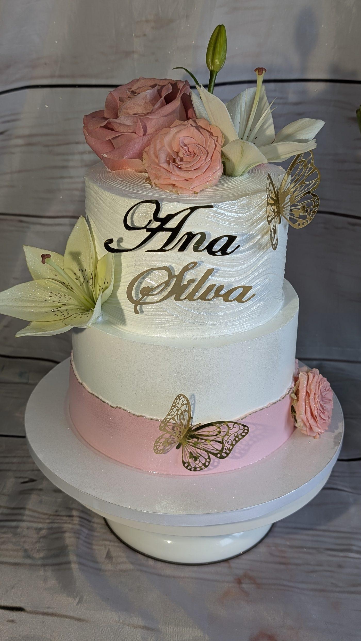Bolo de dois andares com rosas cor-de-rosa e borboletas douradas, criado pela Roberta C Cakes